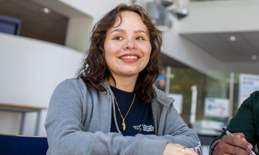 A student called Andrea sat at a desk in the Student Life Building 